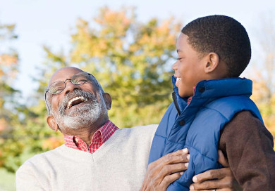 An older African American man laughing with his grandson